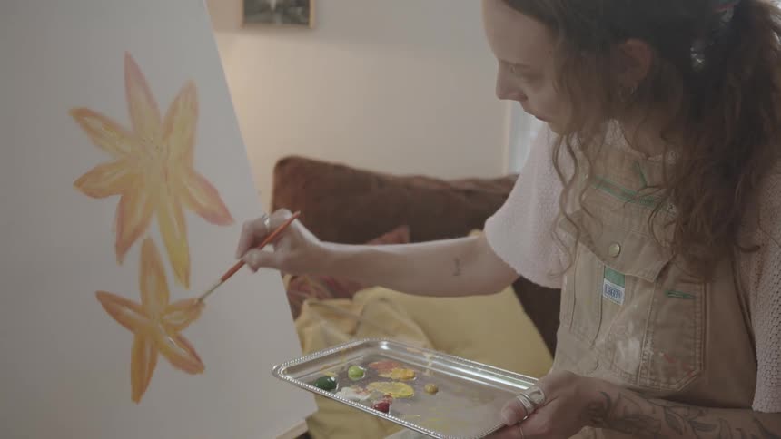 A woman is painting a picture on an indoor canvas