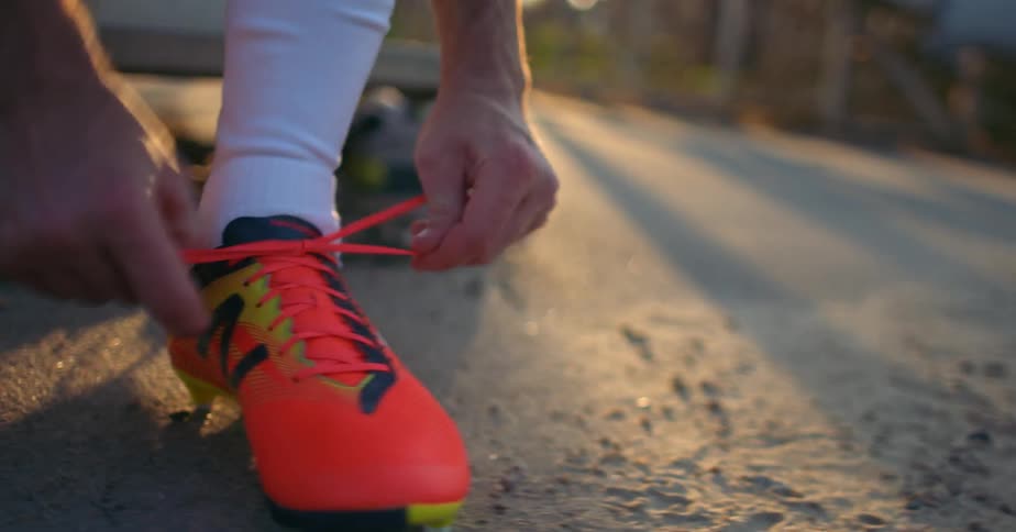 A man ties the laces of his cleats