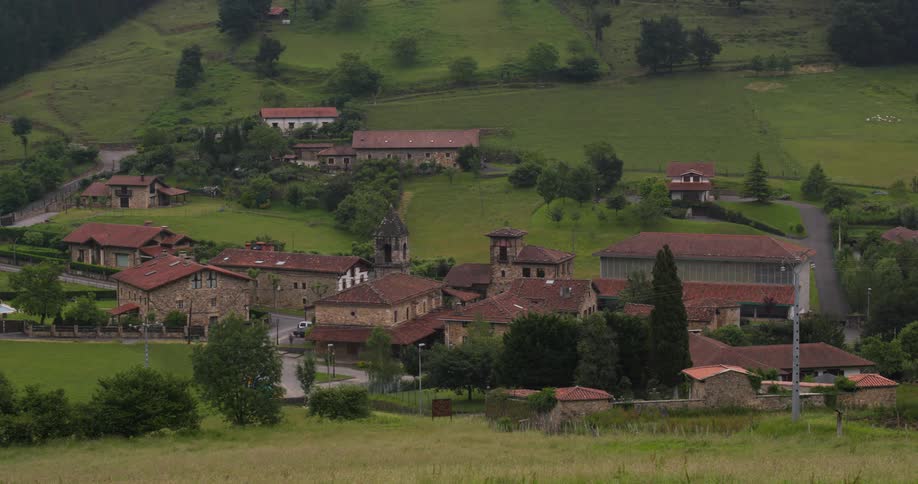 A rural village nestled in a green valley in axpe spain with traditional stone houses featuring red tiled roofs scattered across the landscape