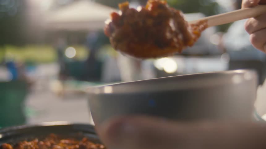 A person serves chili at a picnic