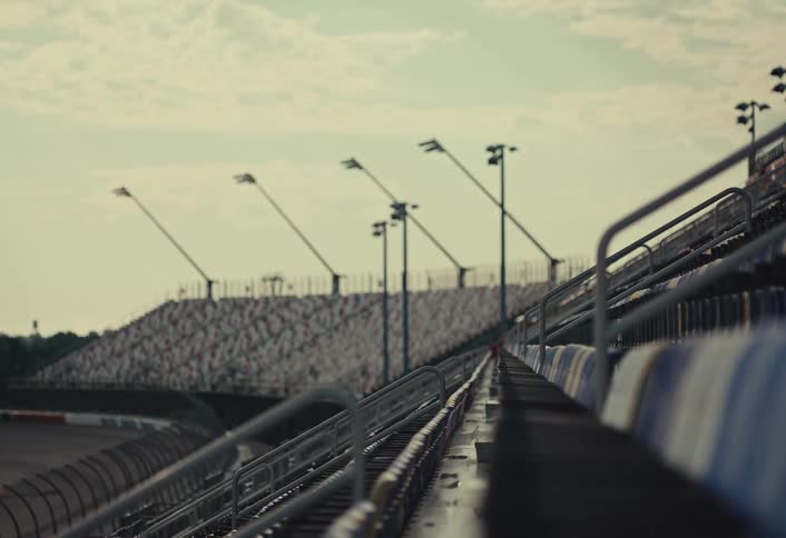 Close up of metal bleachers in an outdoor stadium are under a partly cloudy sky
