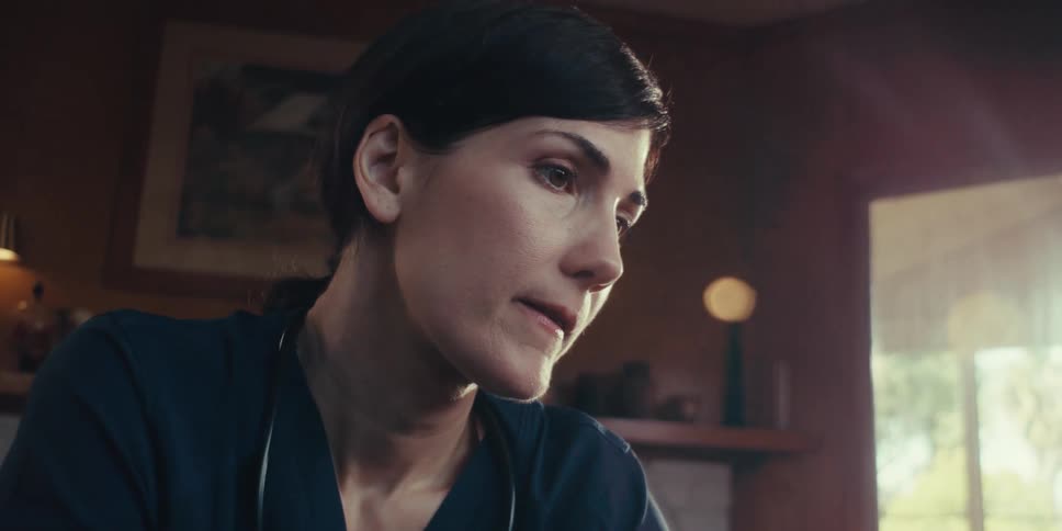 A healthcare professional wearing a dark scrub top talking to the patient