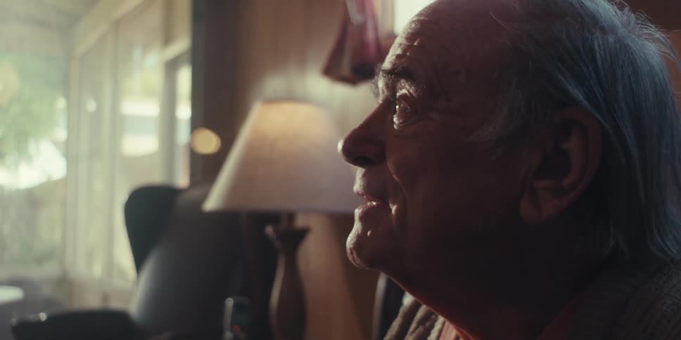 Side portrait of a sitting elderly man talking smiling