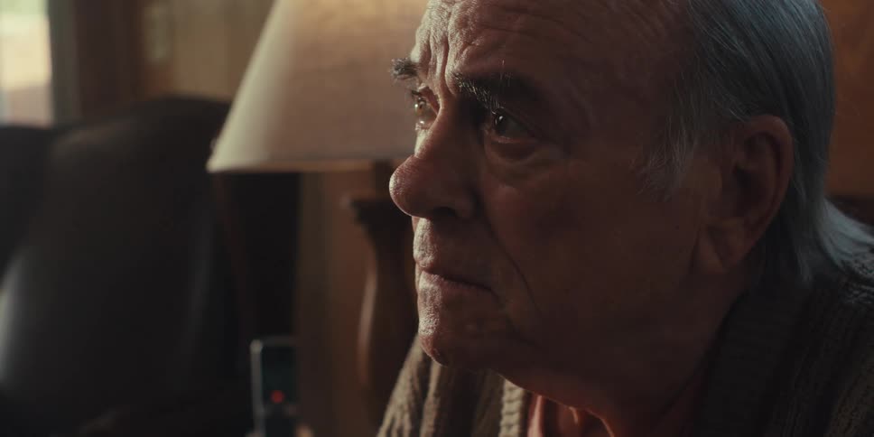 A closeup of an elderly mans face as he looks up at someone with an attentive expression