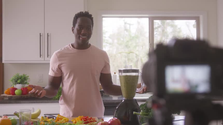 A man is filming himself blending fruit