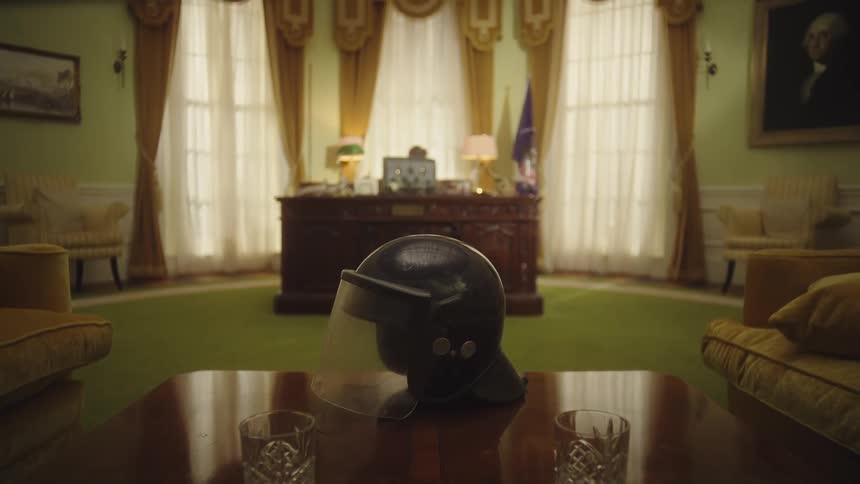 Two crystal glasses and a black helmet with a visor placed on a wooden table in a formal office setting with a wooden desk visible in the background