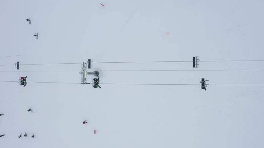Aerial view of people skiing on a snowy mountain and others riding a ski lift