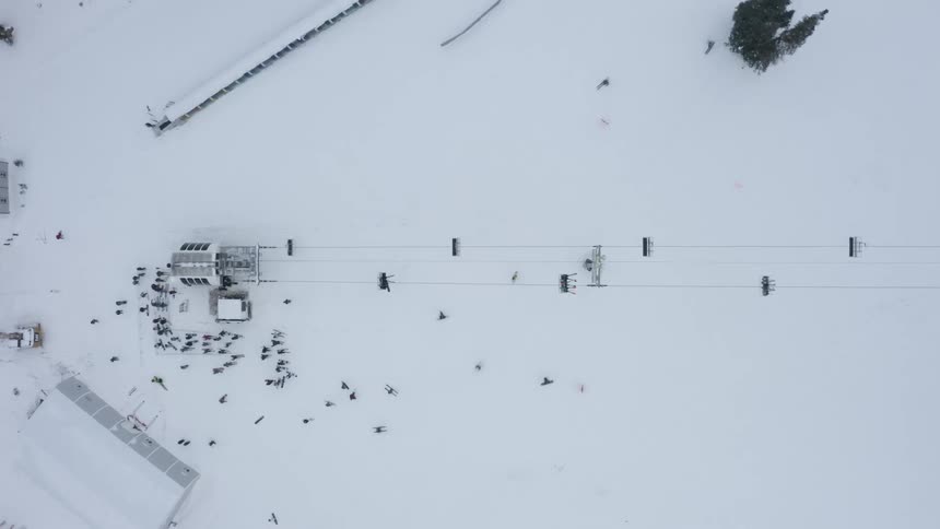 Aerial panorama of a snowy mountain park with ski lifts and people skiing
