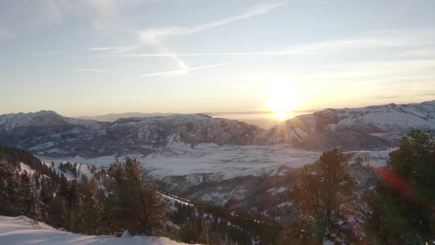 Aerial landscape of snowy mountains and sunrise on the horizon