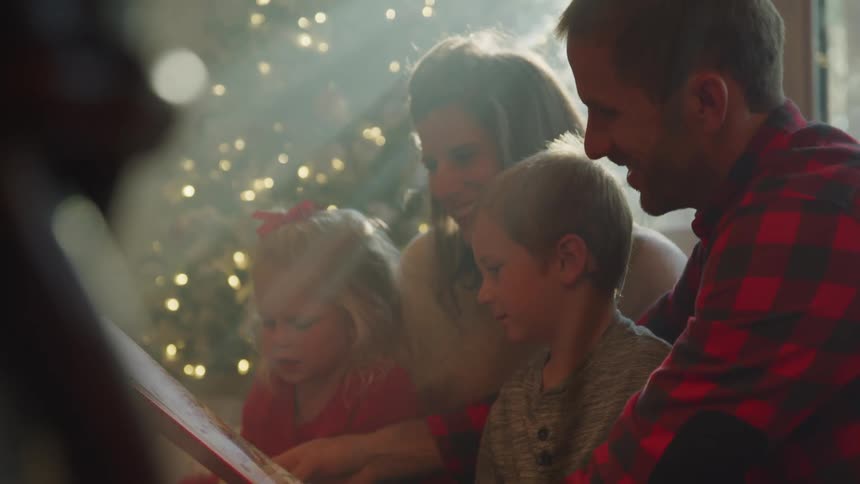 A family read a book by the christmas tree