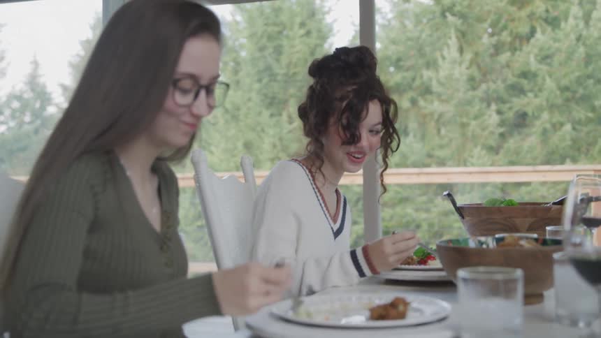 Two young teenage girls sitting at a table served with a lunch eating