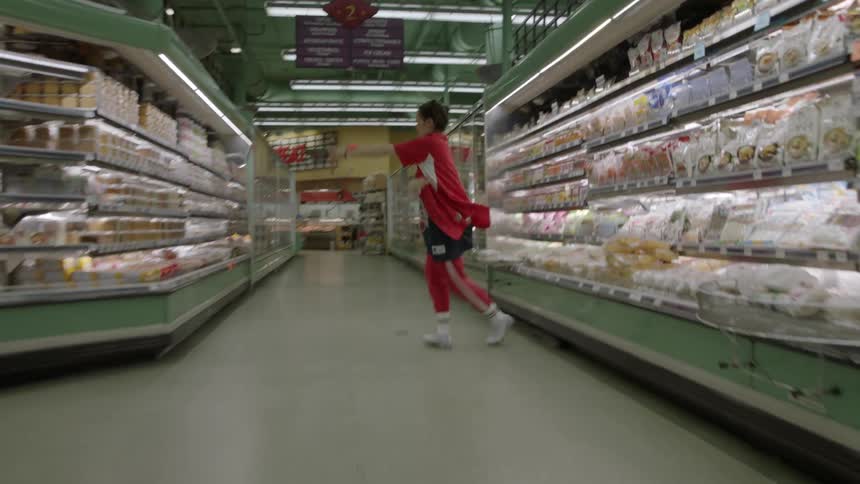 Woman dances in the aisle of a grocery store