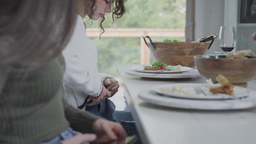 Two young teenage girls sitting at the table and taking a smartphone