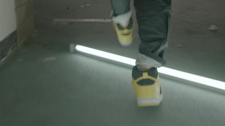 Person wearing sneakers walking a pathway stepping over lighted tubes that are there in a pattern