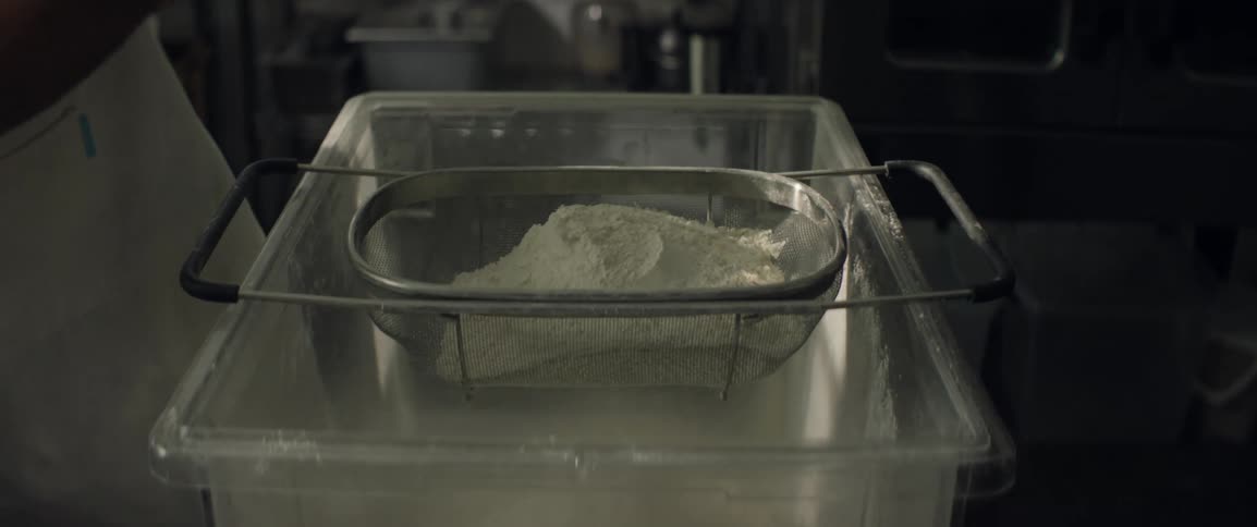 A man is straining flour in the kitchen