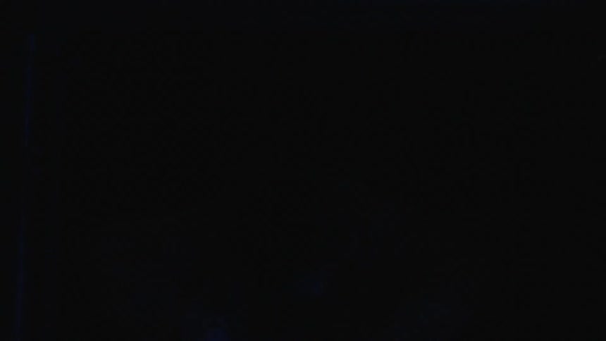 Woman dances in the dark with blue light occasionally flashing