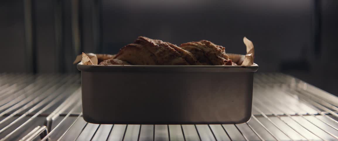 A loaf of bread in a metal container baking in an oven