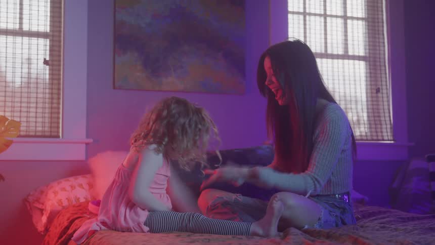 A mother and daughter play on a bed
