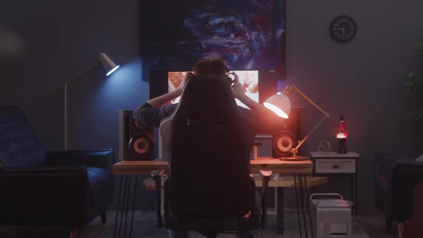 Male sitting in front of a computer puts on headphones