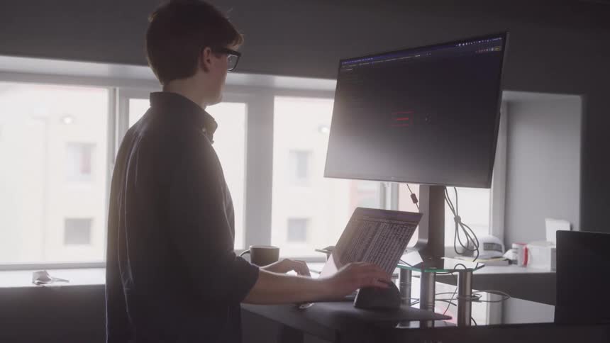 Man working in front of a screen and a laptop