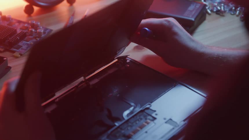 Pair of hands fixing the hardware system of a laptop