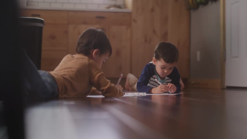 Two little boys lying on the floor drawing