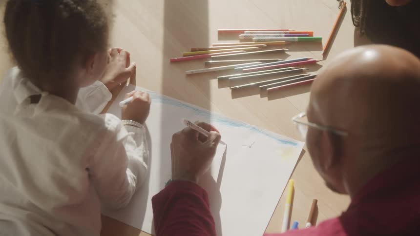 Child drawing accompanied by an adult
