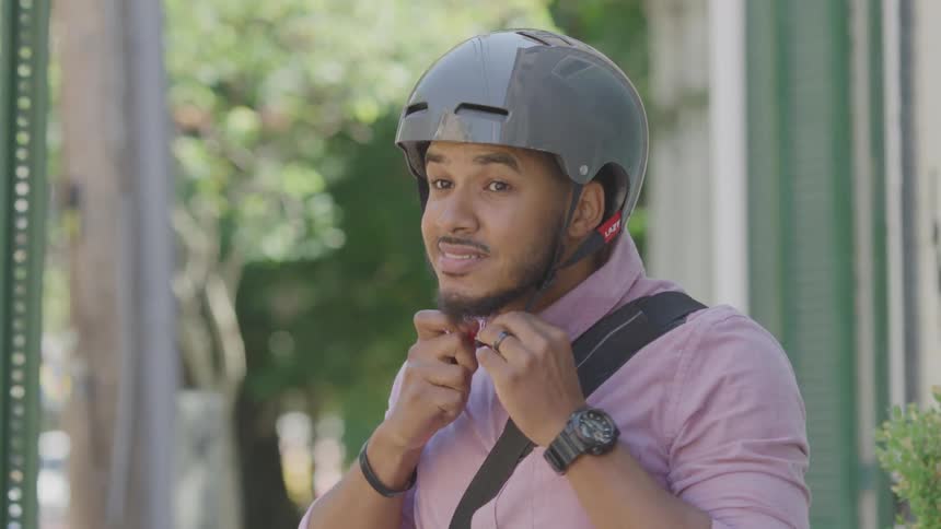 A man puts on his bicycle helmet