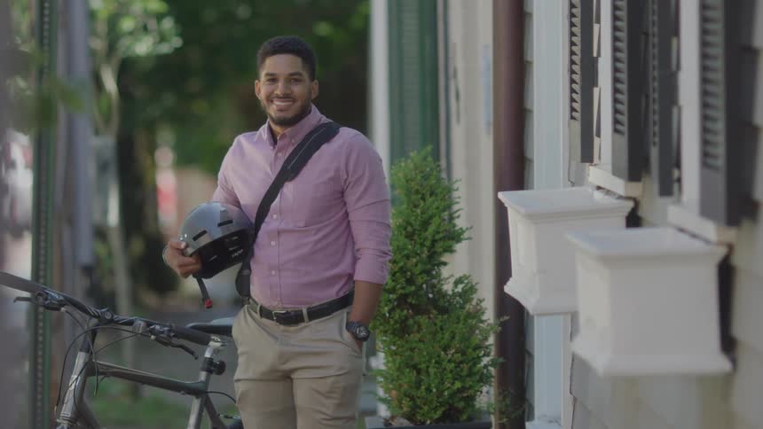 A man holding a bicycle helmet smiles
