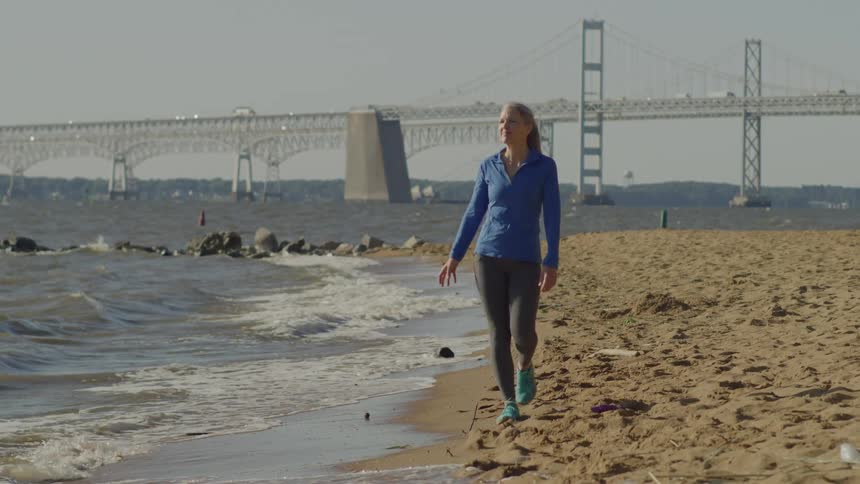 Smiling woman walking on the sand at the beach