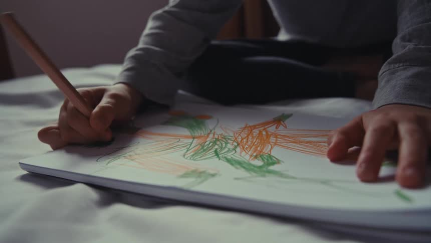A child draws while sitting in bed