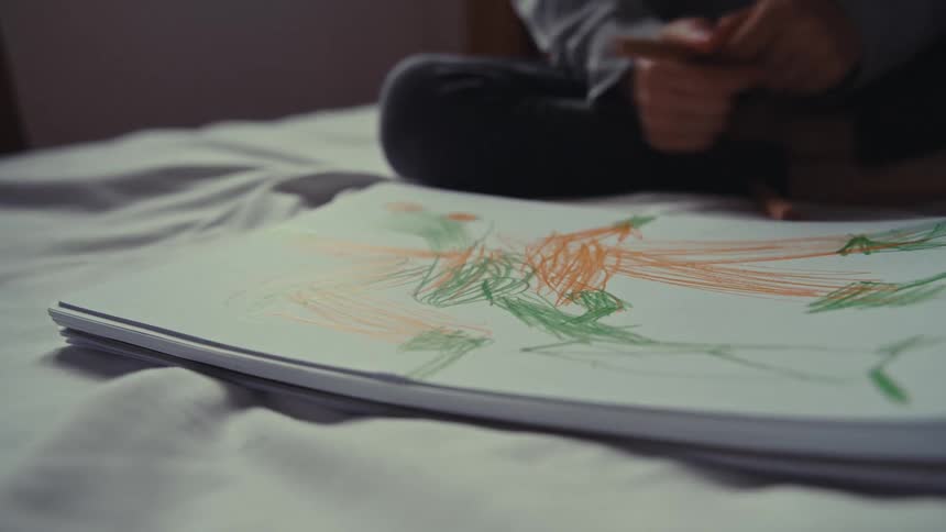 Child drawing and doodling in a white notebook