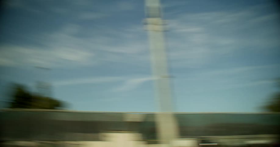 A disorienting and rapidly moving pointofview shot captures the heavily blurred sky and landscape features punctuated by bright sunlight and lens flares