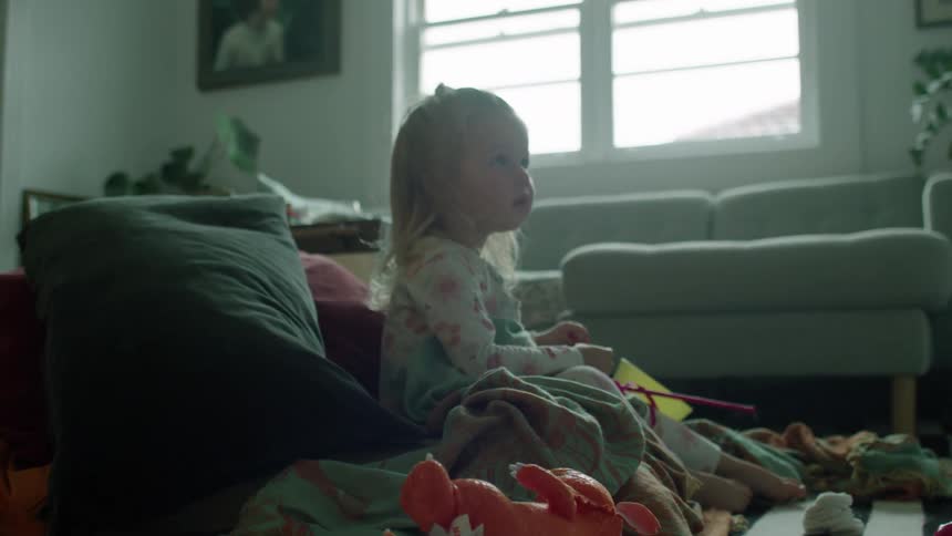 A girl is sitting with her toys on the carpet
