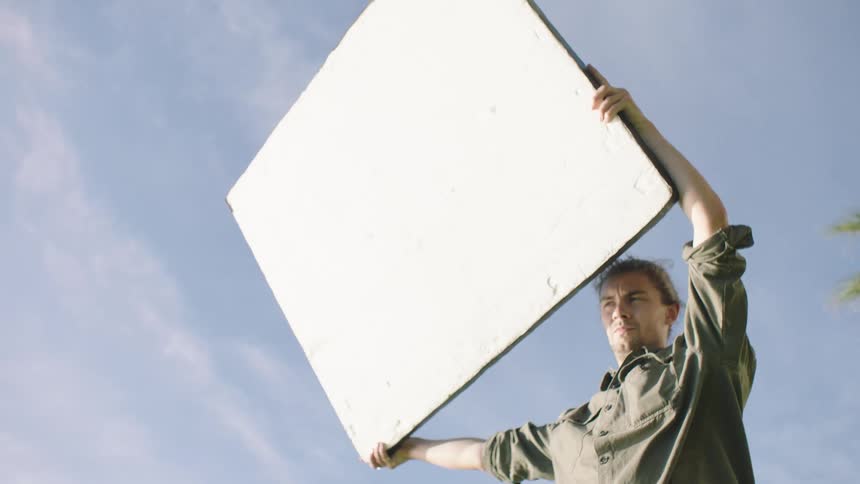Man holding a white sign up outdoors