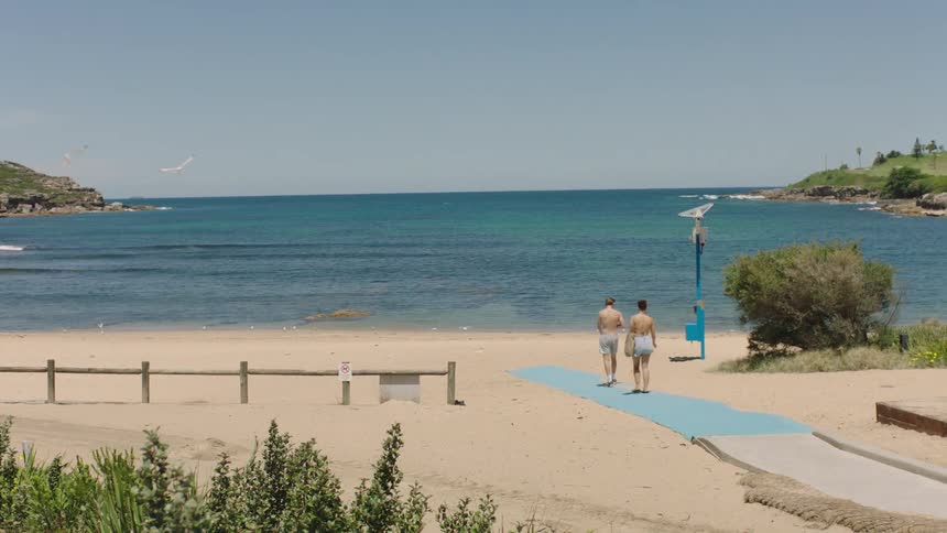 Two people walking towards the sea from the beach