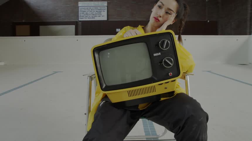Woman sitting on a chair looking bored with a tv on her lap