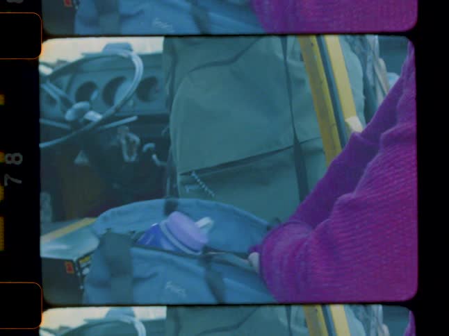 A blonde man stands next to a yellow van and puts a towel into a duffle bag