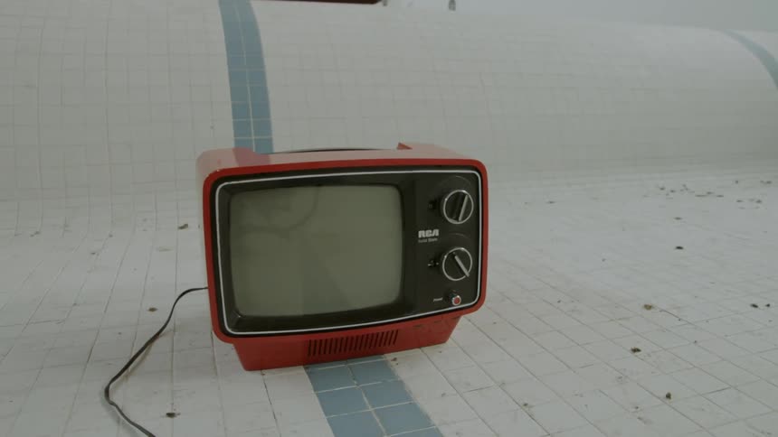 Tv on the floor of an empty indoor pool