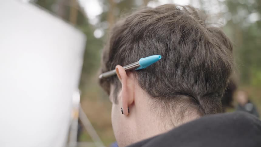 A man has a pen behind his ear