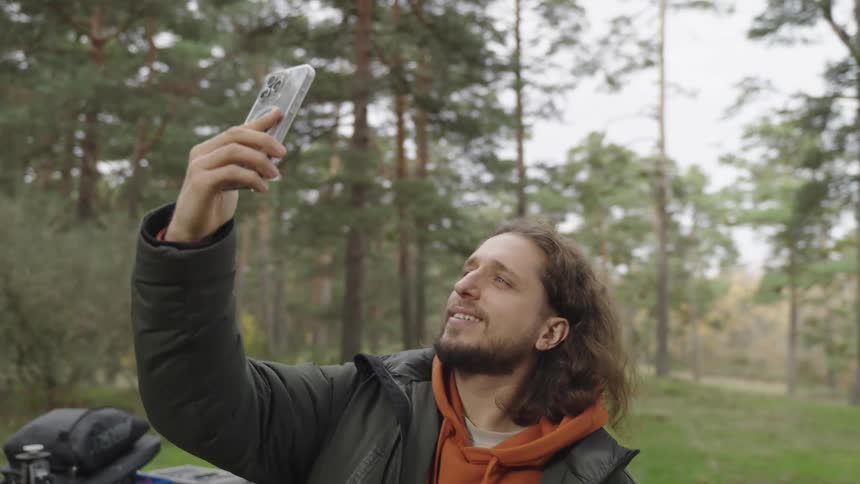 A man is taking a selfie in the woods