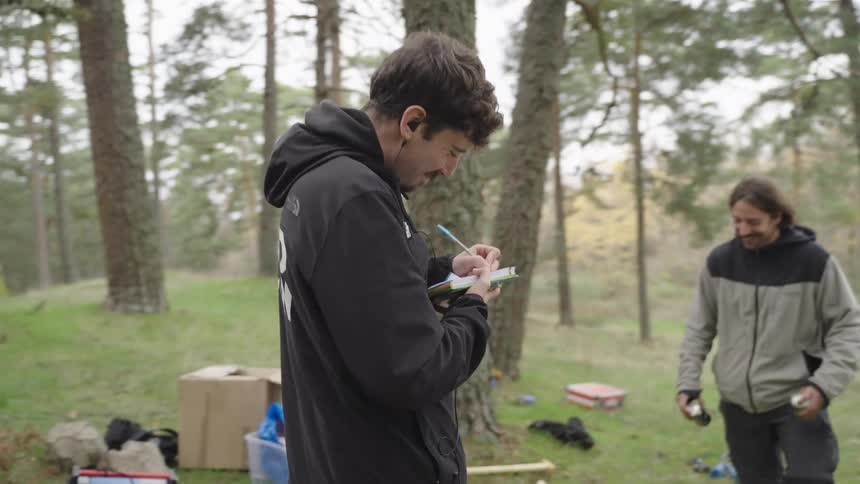 A man is taking notes in the forest on a film set
