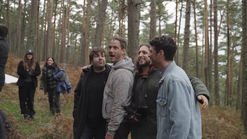 Woman photographing a group of men on a film set in the forest