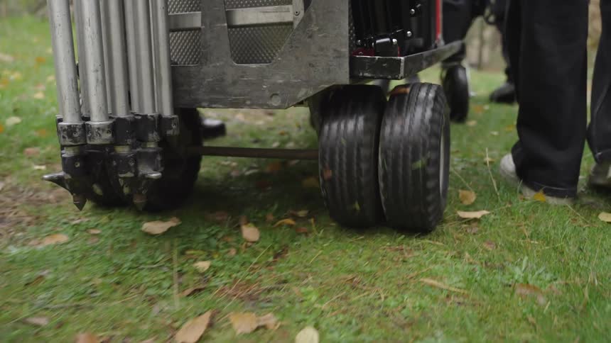 Two people walking next to a portable wheeled device