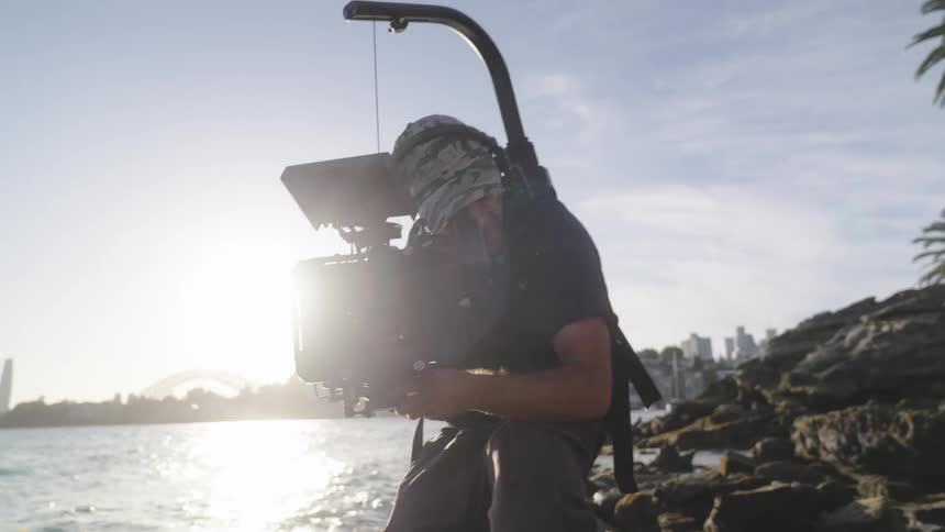 A filmmaker films a scene on a tropical ocean coast