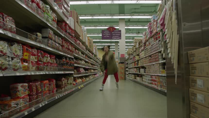 A woman dances and jumps down a grocery aisle