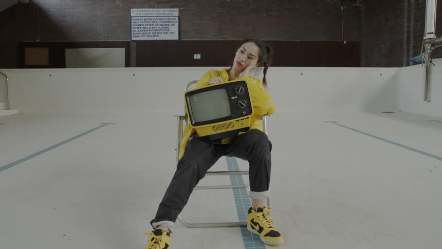 Woman looking bored holding a tv on her lap
