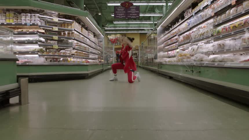 Woman dancing in the middle of a grocery store aisle