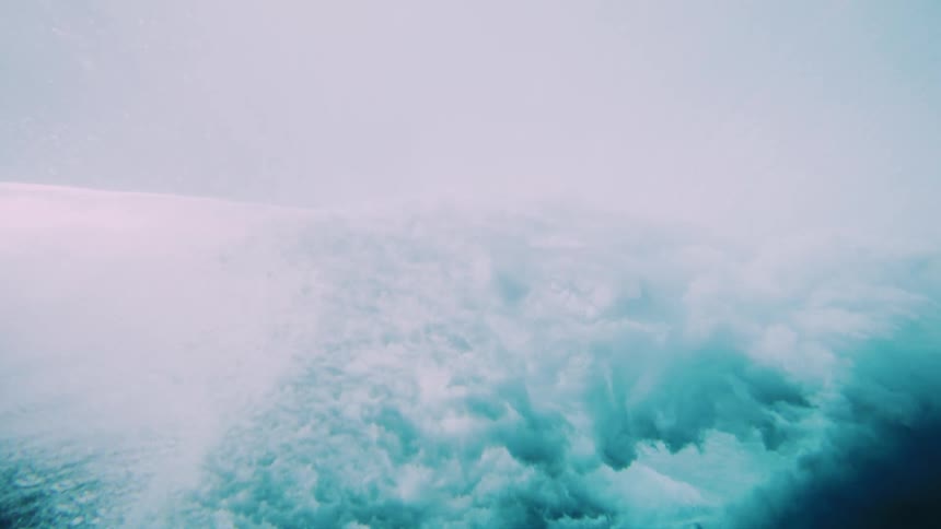 Underwater view of a strong tubular one breaking in the ocean and generating foam impact
