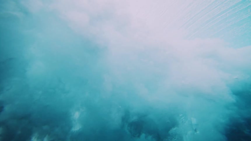 Underwater view from ocean floor of wave crashing above